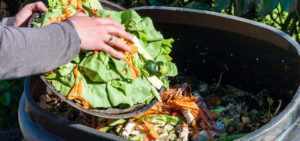 woman putting food scraps into a compost bin